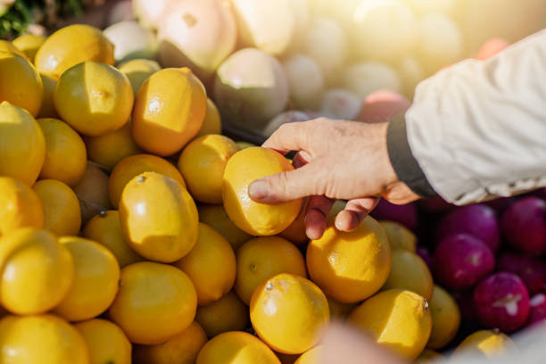 istock Man's hand choosing lemons at local market 2184115059