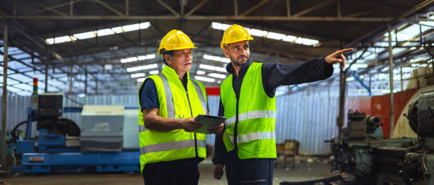 istock Two men in safety vests are pointing at a machine 2184115555