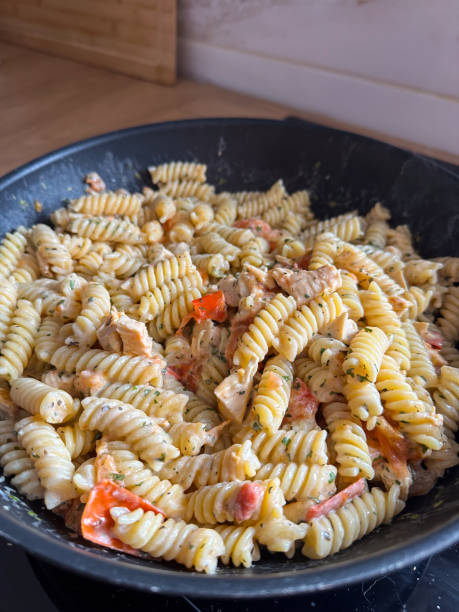 Delicious bowl of creamy rotini pasta mixed with pieces of chicken and vibrant vegetables is served fresh and ready to eat. Dish showcases a perfect blend of flavors and textures, making it an appetizing choice for any meal