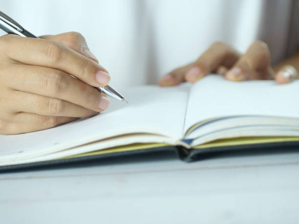 istock Hand holding pen writing on note paper. Finance business concept. Copy space. 2184121004