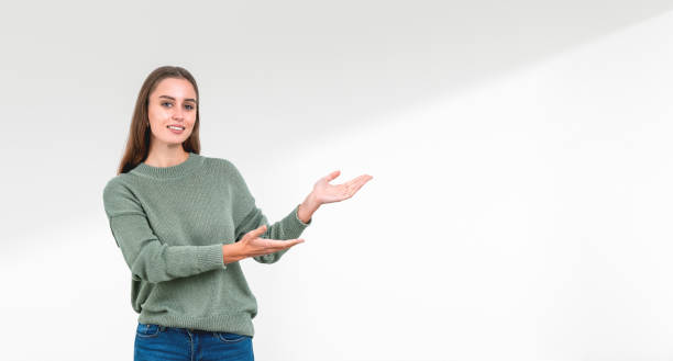 istock Woman showing empty copy space with a gesture, portrait on a light background, concept of presentation 2184122568