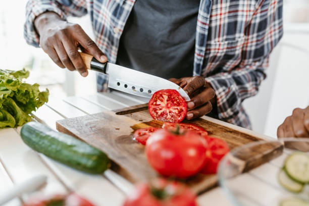 istock Person Slicing Fresh Tomatoes in a Modern Kitchen 2184123021