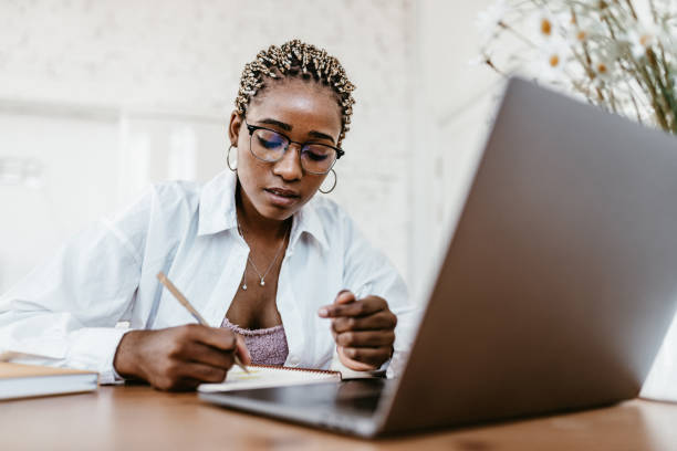 istock Young Professional Woman Working Remotely on Laptop at Home 2184123156