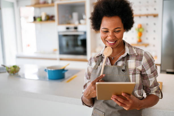 istock Young african american woman using a tablet computer to cook in her kitchen 2184123425