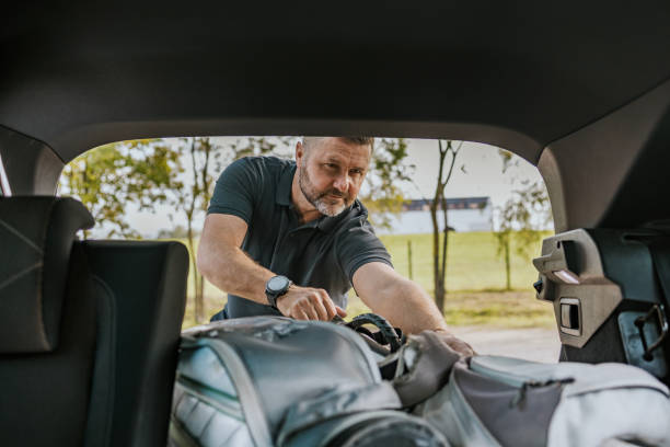 istock Man retrieving golf clubs from car trunk on a sunny day 2184125962