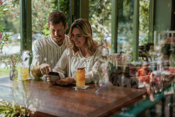 istock Couple looking down at a smartphone while sitting in a cafe 2184125979