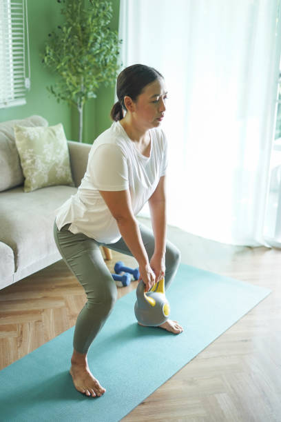 istock Woman lifting dumbbells, exercising indoors 2184126620
