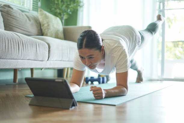 istock Woman looking at tablet exercising on yoga mat 2184126682