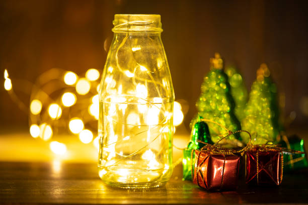 istock Orange lights in a glass bottle with Christmas gift boxes. 2184127038