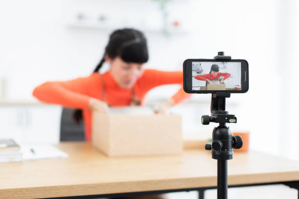 istock Caucasian female blogger creating unboxing video with smartphone camera 2184130052