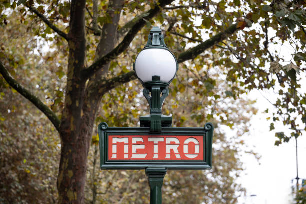 A traditional Parisian metro sign in the foreground, framed by ornate historic balconies and building facades. Captures the essence of Paris street life and its iconic design aesthetics.
