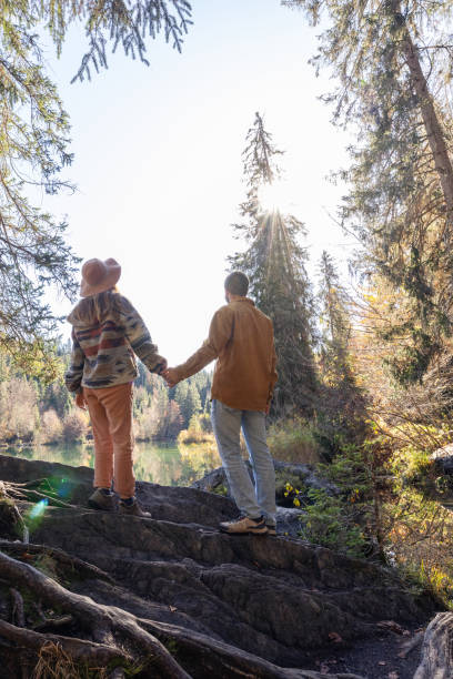 istock Couple Holding Hands in Forested Lakeside Landscape 2184130795