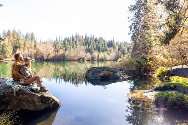 istock Couple Relaxing on Lakeside Rock in Autumn Forest 2184130895