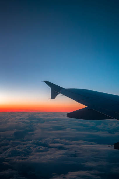 istock An airplane wing over a blanket of clouds, with a gradient sunset or sunrise 2184132922
