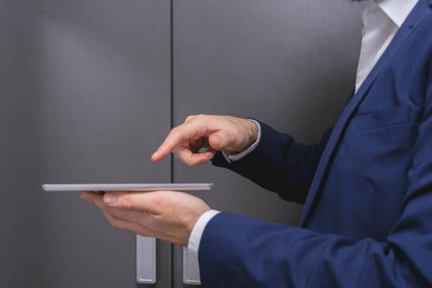 istock Close-up of businessman using digital tablet while standing in locker room 2184133830