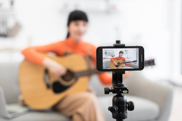 istock Caucasian female recording guitar tutorial at home on smartphone 2184134790
