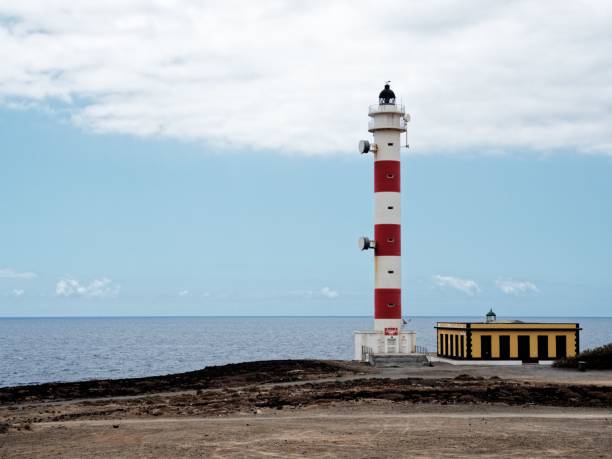 istock Red and white lighthouse on a rocky coastline. 2184134795