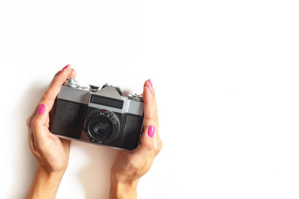 female hands hold vintage camera on white background