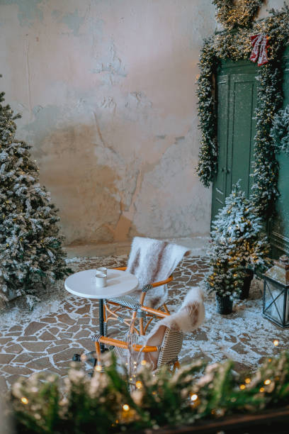 istock Cozy winter corner with a small table and decorated trees in a rustic room 2184135704
