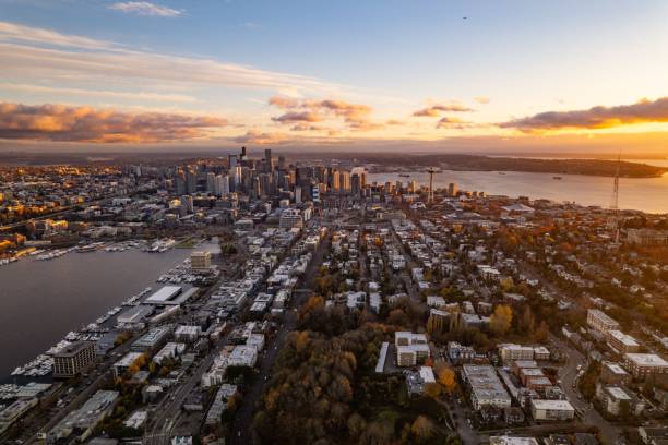 Aerial view of Seattle skyline at sunset, featuring Space Needle and Elliott Bay, with vibrant autumn colors.