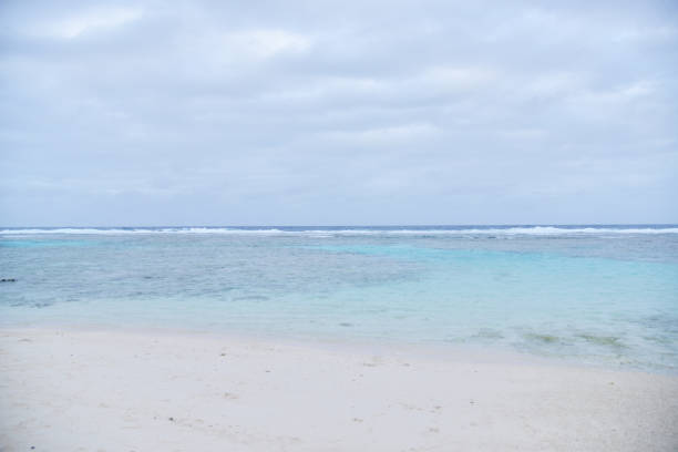 White sand beach with sapphire sea water under clouds