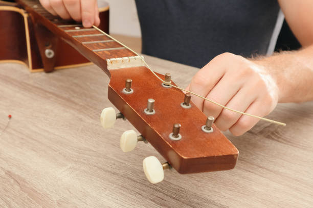 istock Hands of a young man changing the string on an acoustic guitar. Hand fixing guitar. 2184137782