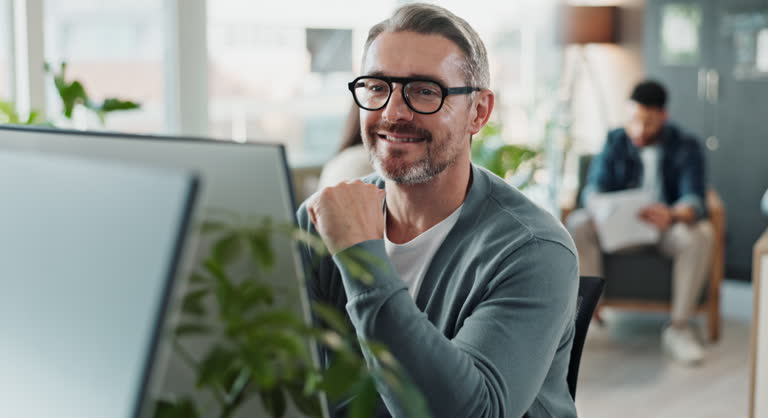 Computer, solution and web development with happy man software engineer in office for coding or programming. PC, reading and typing with smile of mature employee in workplace for design or research