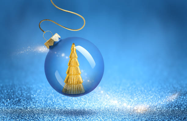 istock Christmas bauble with gold tree decoration inside. New Year ornaments on blue sparkling background. 2184142745