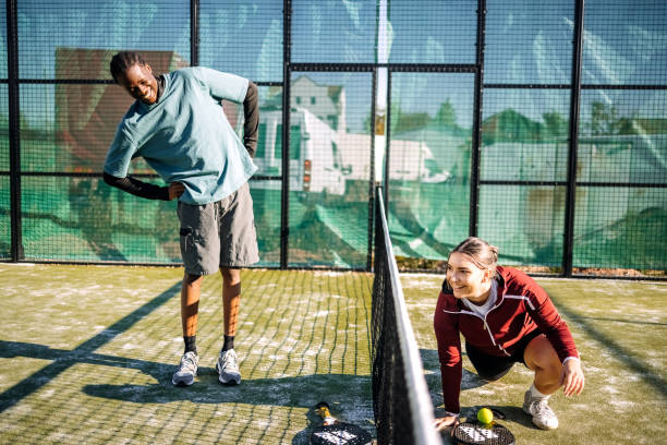 istock Young adults stretching before playing badel on sport court 2184143935