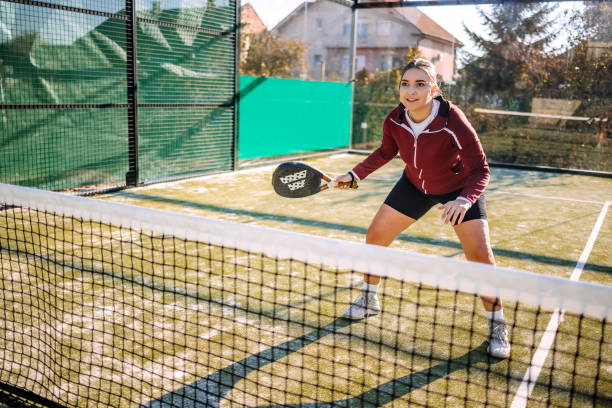 istock Young woman playing badel on sport court taking a shoot using racket 2184144115
