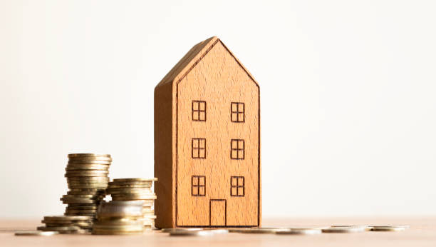 istock Real estate concept background. House model and coins stack on wooden table, copy space. 2184146733