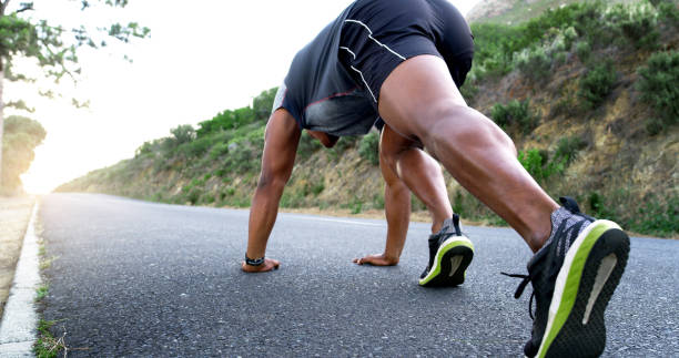 istock Man, runner and stretching for exercise on mountain road with warm up, start and low angle with legs. Person, fitness and training with wellness, health and outdoor for performance 2184147628