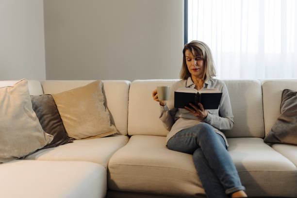 istock Senior woman reading book at home 2184147884
