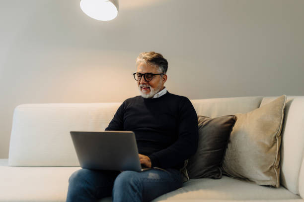 istock Mature adult man using laptop at home 2184147900