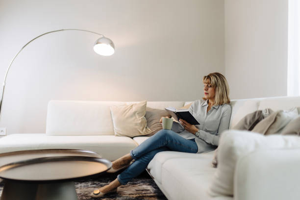 istock Senior woman reading book at home 2184148385