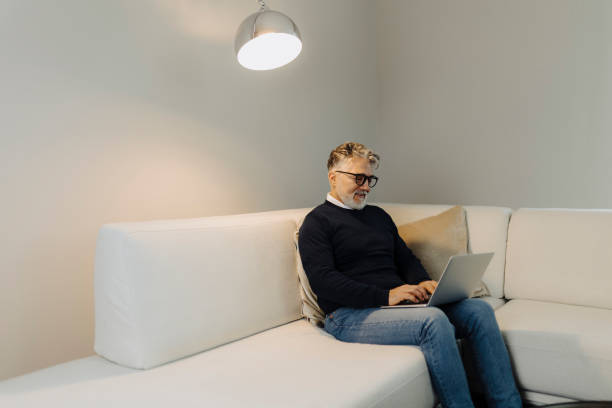 istock Mature adult man using laptop at home 2184148467