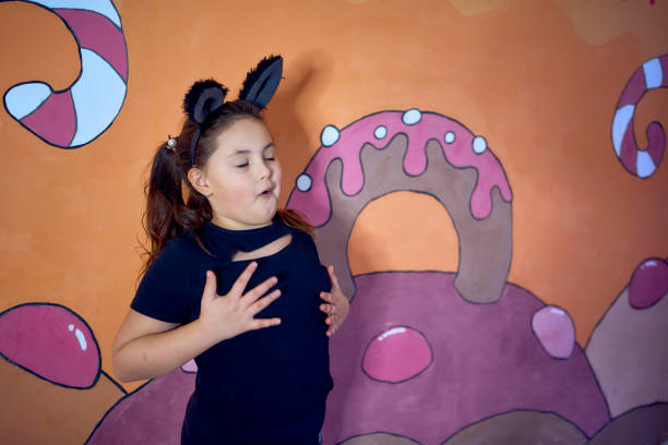 A four-year-old girl holds and shows pine cones that she has painted with tempera.
