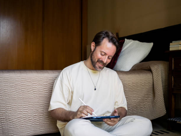 istock Man sketching on a tablet while sitting on the floor in a cozy room 2184152615