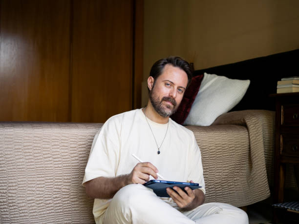 istock Illustrator looking at camera while sketching on a tablet seated on the floor 2184153187