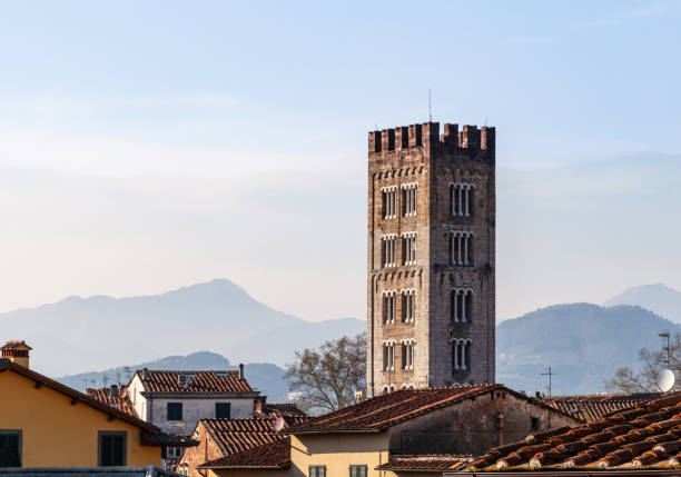 Guinigi tower standing tall over the rooftops of lucca, italy, with the tuscan mountains providing a scenic backdrop