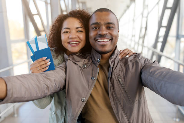 istock Vacation. Happy Black Spouses Making Selfie Showing Passports Smiling To Camera Posing At Airport Outdoors. Great Travel Offer And Tourism Service Concept. Selective Focus 2184155014