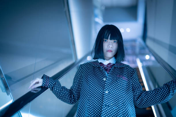 Woman moving down on escalator in city at night
