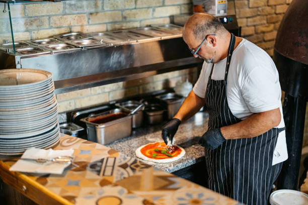 istock Mature Chef Making A Pizza In A Commercial Kitchen 2184162626