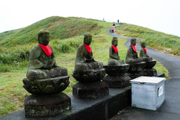 Mount Omuro Sengen Shrine, Mount Omuro, Ito, Japan- 29 Oct 2024: The Five Great Buddhas with red scarf from the side view with mountain hill at the bad and path
