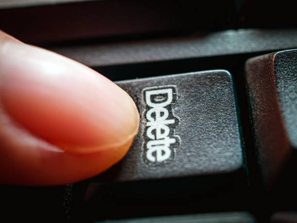 Close-up of finger pressing the Delete  key on the keyboard.