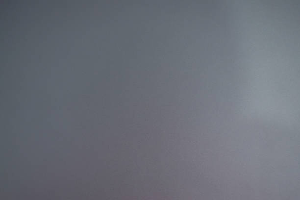 A close-up image of a smooth, metallic surface with a soft gradient in a blue-gray tone. The surface has a slightly textured, matte finish, giving a minimalist and modern feel
