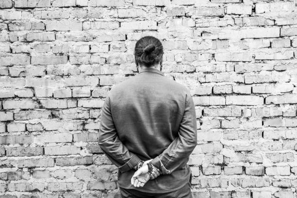 istock A dark-haired man with long hair in a shirt stands facing a brick wall 2184170197