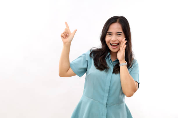 istock Excited young woman, expresses positive emotions indicates away on blank copy space shows something pleasant, isolated white background 2184170832