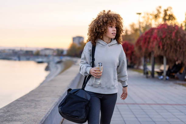 istock Woman strolls along riverside path, holding water bottle 2184170835