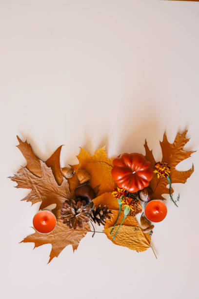 istock Autumn flat lay with leaves, pine cones, acorns, mini pumpkin, and candles arranged on a light background for seasonal decoration 2184173036